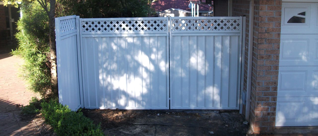 Painted timber double driveway gates with lattice top panels installed across a residential driveway in Sydney
