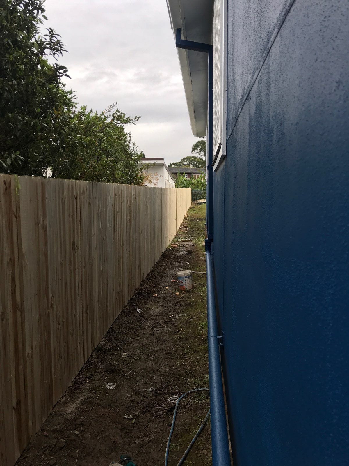 Treated pine timber fence built beside a dark rendered wall along a Sydney side boundary